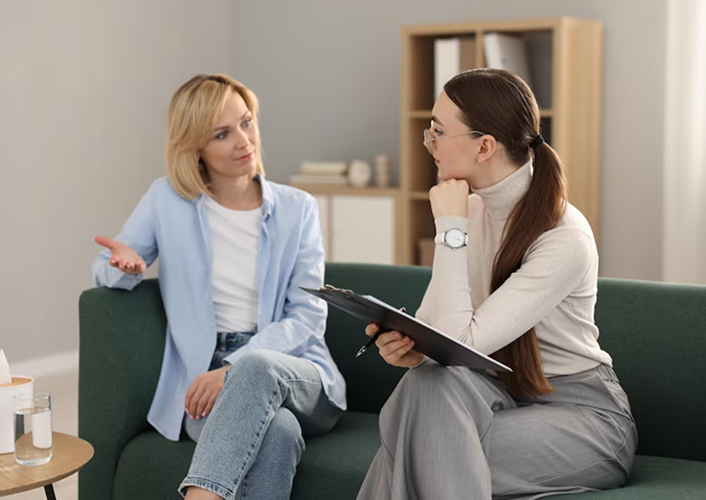 A coach listening closely as a client talks through a hard day, seated together on a green couch